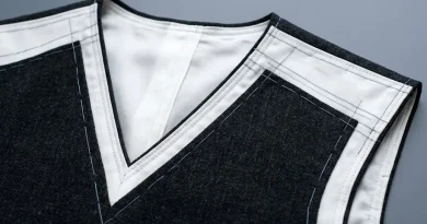 Detalle lineal y limpio de los cortes y costuras de un cuello en V iluminado frontalmente en un vestidor premium.